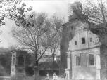 (21/48): Kościół parafialny św. Jana Chrzciciela<br>fot. n.n., XIX/XX w.<br>Widok kościoła od południowego-wsxhodu. Na pierwszym planie po prawej stronie kaplica M.B. Szkaplerznej (dawn. Św. Anioła Stróża) z wieżą kościoła w tle. Po lewej stronie figura św. Wawrzyńca (barokowa z XVIII w.) i kapliczka N.M.P. (klasycystyczna). Na drugim planie budynki przy ulicy Szerokiej (ob. Maślanej).